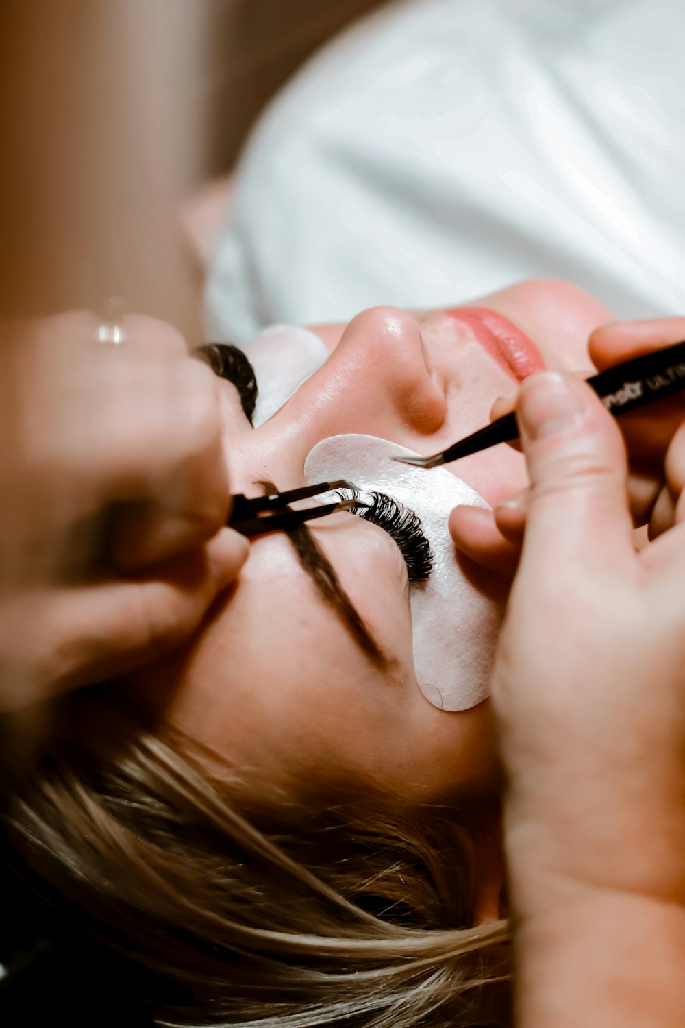 Lash extensions being applied with tweezers