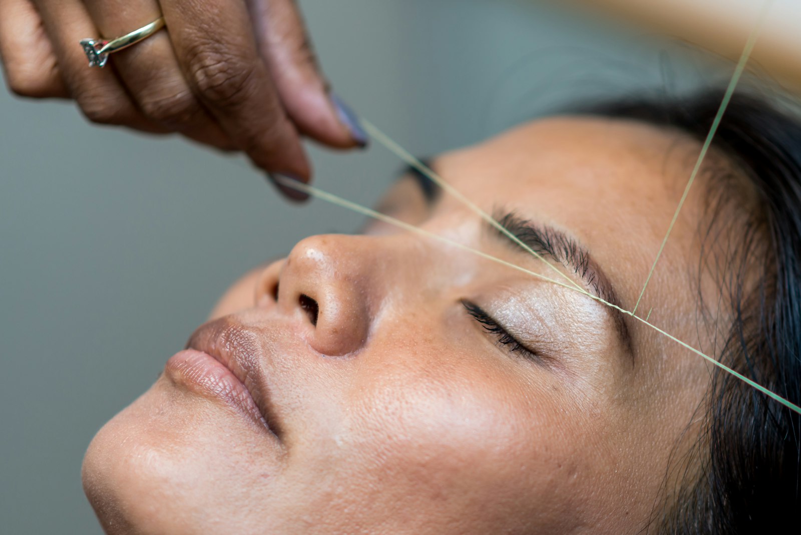 An eyebrow being shaped with a twisted cotton thread
